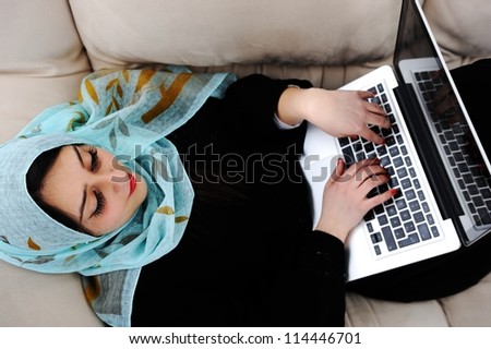 Young woman with laptop lying on couch