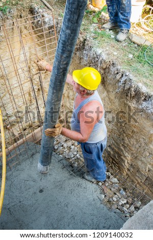 Worker pouring concrete mix at home foundation