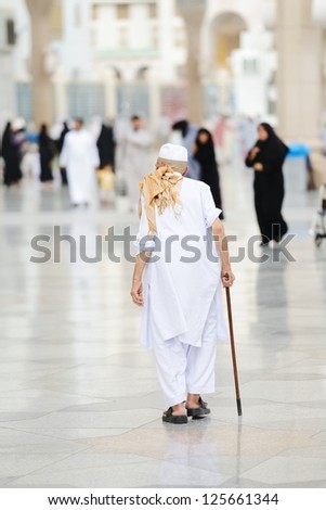 Aged Muslim pilgrim walking in front of Mecca mosque