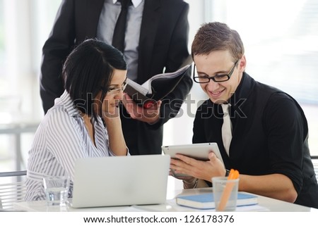 Three business people working at office with paperwork using tablet and laptop