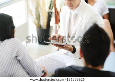 Portrait of modern couple talking to manager while discussing conditions of mortgage using tablet