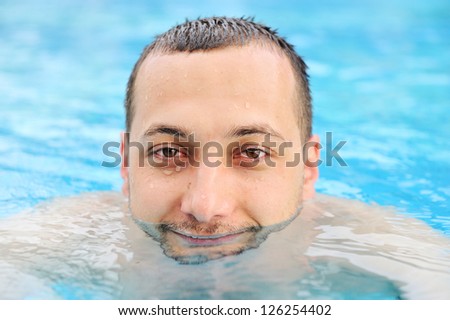 Closeup portrait of a handsome funny and happy young man in pool