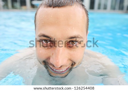 Closeup portrait of a handsome funny and happy young man in pool
