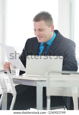 Relaxed executive sitting on desk in office