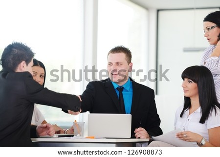 Happy business people shaking hands on a deal and smiling over working table