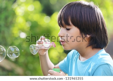 Portrait of cute little boy making soap bubbles. Free copy space