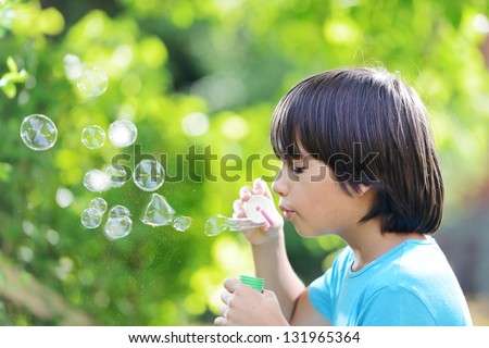 Portrait of cute little boy making soap bubbles. Free copy space