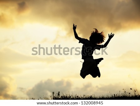 Active little boy jumping and having happy time on summer meadow by sunset