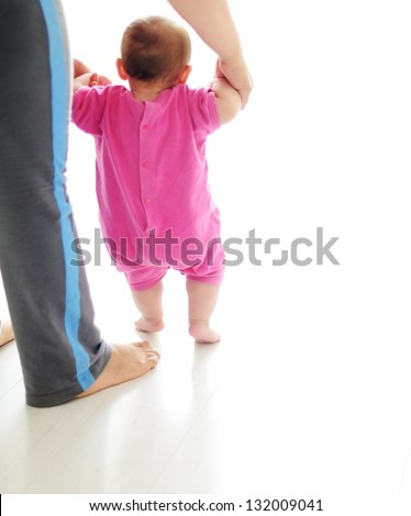 Baby taking first steps with mother help on white background