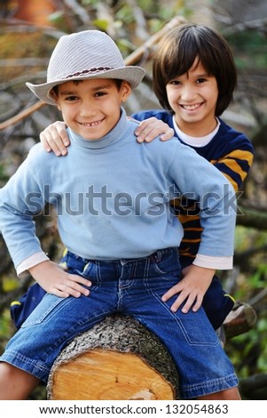 Two children portrait on timber tree outdoor in nature