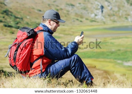 Man sitting on mountain and searching for mobile signal