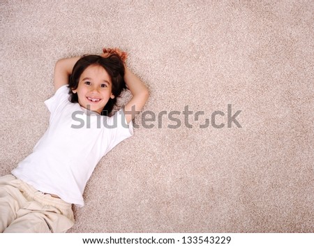 Little boy lying on carpet floor at home and smiling