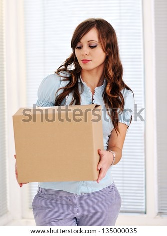 Young woman lifting a heavy cardboard moving box