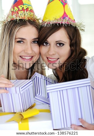 Two beautiful caucasian girls celebrating birthday wearing holiday hats