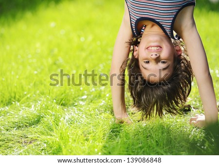 Portraits Of Happy Kids Playing Upside Down Outdoors In Summer Park