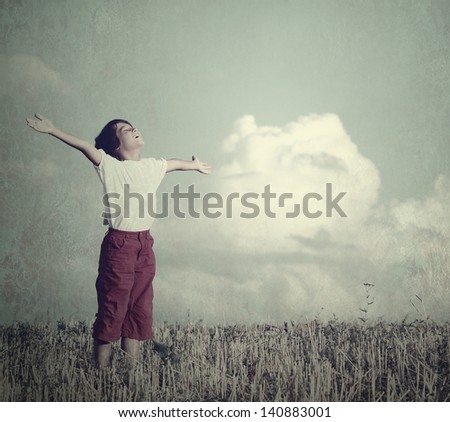 Free child dreaming with outstretched hands on beautiful meadow with clouds in background