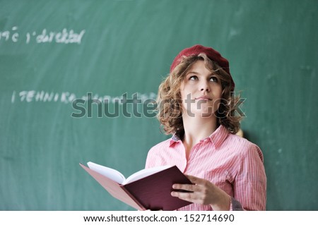 Student with a red french cap thinking in front of a chalkboard