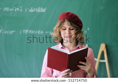 Student with a french cap reading a book in a classroom