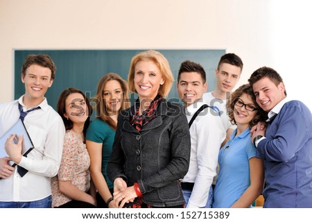 Students posing with their teacher in front of a blackboard Students posing with their teacher in front of a blackboard