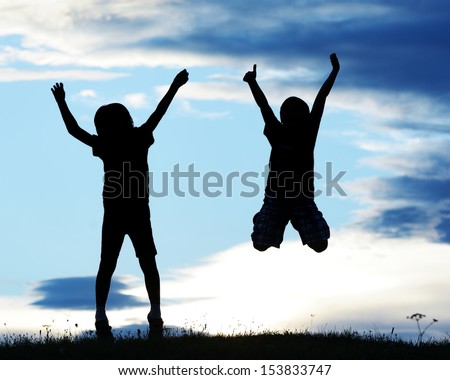 Happy kids silhouettes having fun on meadow at sunset celebrating summer