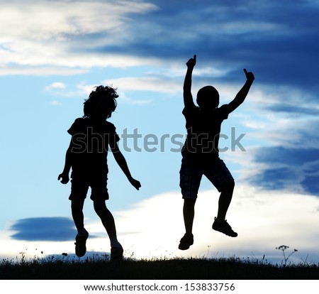 Happy kids silhouettes having fun on meadow at sunset celebrating summer