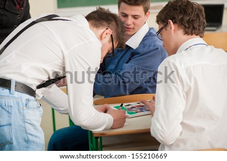 Three neatly dressed students writing in classroom