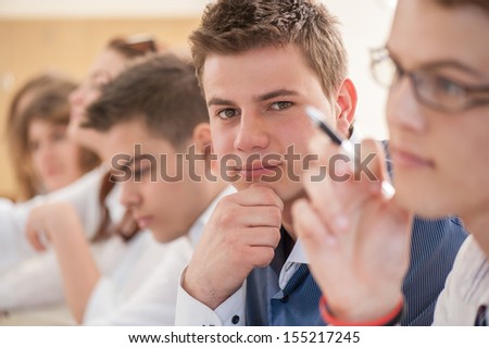Thinking high school student sitting in a class with other students