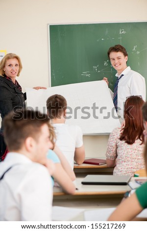 Teacher and a student holding a white banner in a classroom