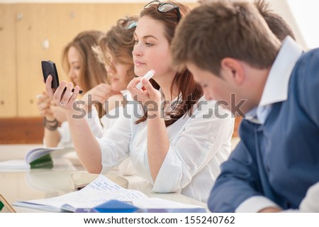 Student with mirror putting a makeup in a classroom