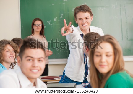Happy student holding up two fingers in a classroom