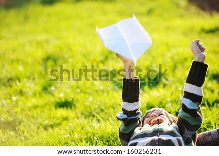 Happy kid enjoying sunny late summer and autumn day in nature on green grass