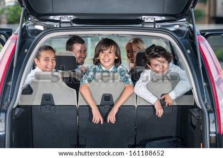 Happy Smiling Family In The Car Looking Backwards Through Open Trunk