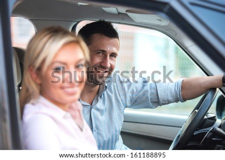 Happy man in a car driving a beautiful happy woman