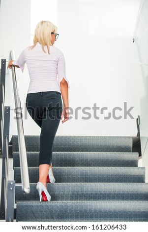 Modern handsome blonde woman climbing stairs