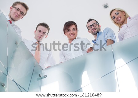 Group of business people posing behind a glass railing