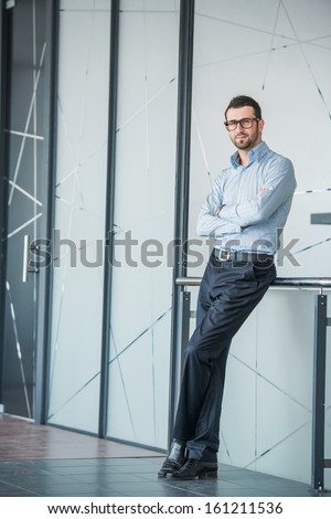 Handsome manager posing by the rail in a company