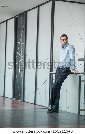Happy corporate man posing in a company environment