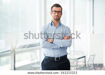 Corporate man standing in office with his arms crossed