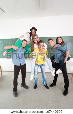 Cheerful classmates playing in classroom in front of a blackboard