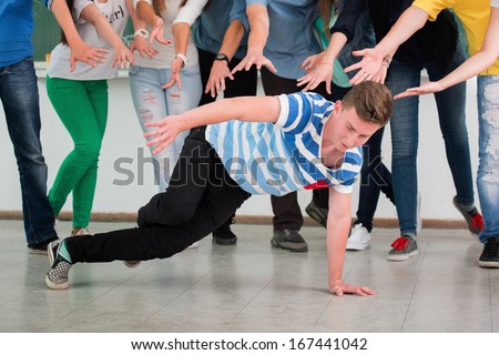 Student break dancing in classroom surrounded by classmates