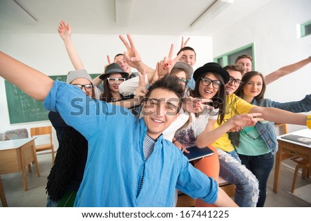 Cheerful Classmates Posing In Classroom In Front Of A Green Board