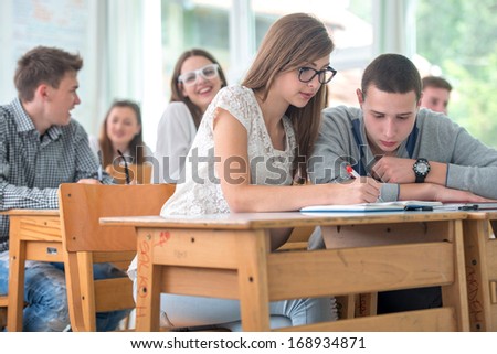 Two highschool students studying together in classroom