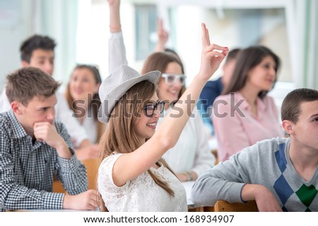 Female student raising hand during lecture in classroom