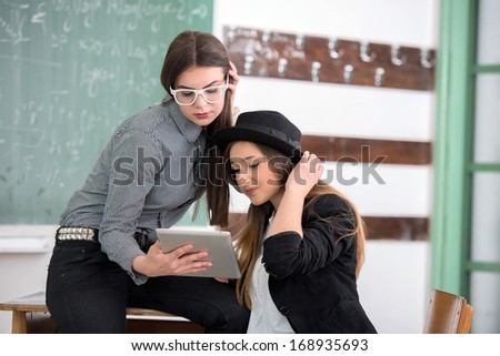 Two cute schoolgirls reading together