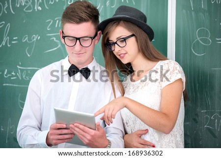 Two smart looking students holding a tablet computer