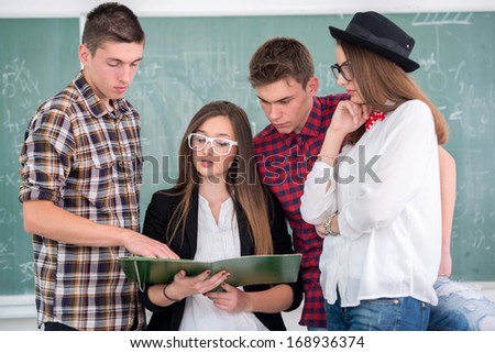 Four teenagers in classroom reading together