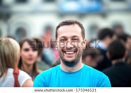 Smiling man standing on a crowded street