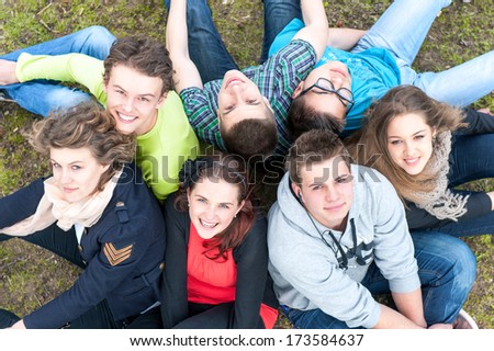 Happy group of teenagers sitting on a lawn shot from above