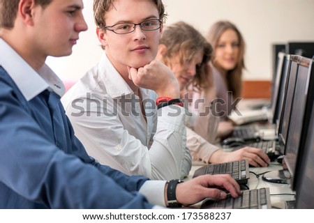 Smart student sitting by computer in classroom with classmates