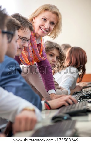Teacher posing with students in classroom by computers